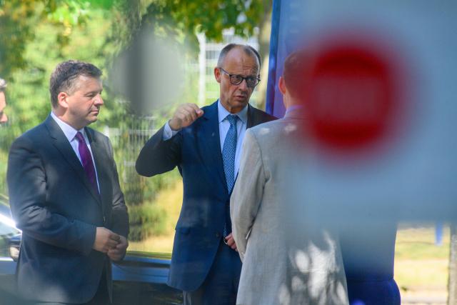 26 June 2026, Saxony-Anhalt, Barleben: Sven Schulze (L), Minister President of Saxony-Anhalt, and German Chancellor Friedrich Merz are greeted in front of the entrance to the Hexal/Sandoz pharmaceutical company. Merz and Schulze toured the site and met with company executives for discussions. Photo: Klaus-Dietmar Gabbert/dpa