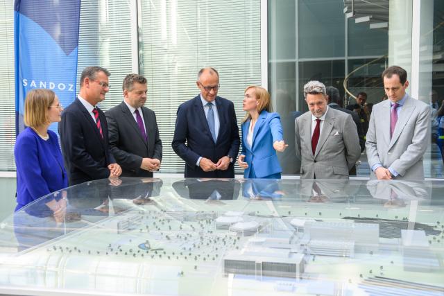 26 June 2026, Saxony-Anhalt, Barleben: Sven Schulze (3rd L), Minister-President of Saxony-Anhalt; and German Chancellor Friedrich Merz (C) stand with corporate employees behind a model of the Hexal/Sandoz pharmaceutical plant site. Merz and Schulze toured the site and met with company executives for discussions. Photo: Klaus-Dietmar Gabbert/dpa