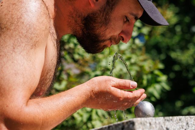 26 June 2026, Sieversdorf: A fan of the American musician Bruno Mars drinks from a fountain on his way to a concert at Berlin's Olympic Stadium. A heat wave is currently sweeping through Brandenburg and Berlin. Photo: Carsten Koall/dpa