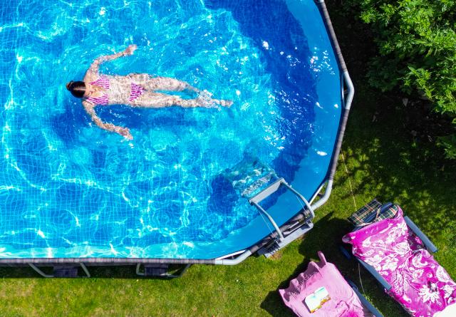 27 June 2026, Brandenburg: A girl cools off in a backyard swimming pool during hot summer weather. Photo: Patrick Pleul/dpa