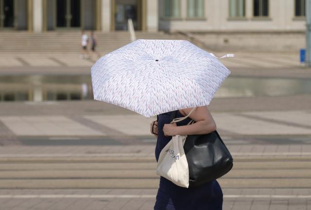 27 June 2026, Leipzig: mbrella to shield herself from the sun during hot weather in Leipzig. Photo: Sebastian Willnow/dpa