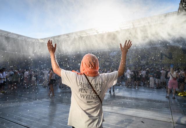 27 June 2026, Saxony, Dresden: A fan of the German band Kraftklub cools off under a water spray during a heatwave before the start of a concert at the 2026 "Sterben in Karl-Marx-Stadt" Open Air festival at Rudolf-Harbig Stadium. Photo: Robert Michael/dpa