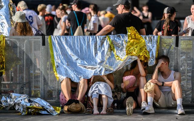 27 June 2026, Saxony, Dresden: Fans of German band Kraftklub shelter from the sun under emergency tarps during a heatwave before the start of a concert at the 2026 "Sterben in Karl-Marx-Stadt" Open Air festival at Rudolf-Harbig Stadium. Photo: Robert Michael/dpa