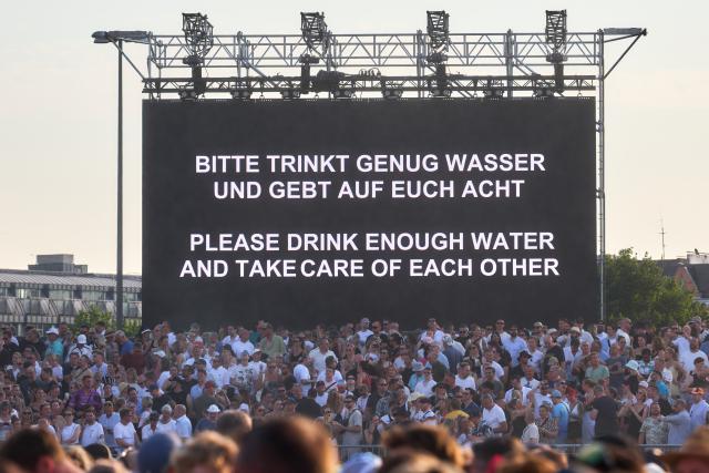 27 June 2026, Hamburg: The message "Please drink enough water and take care of each other" is displayed on a screen amid soaring temperatures during a concert by techno star Paul Kalkbrenner on the Heiligengeistfeld in Hamburg. Photo: Marcus Golejewski/dpa