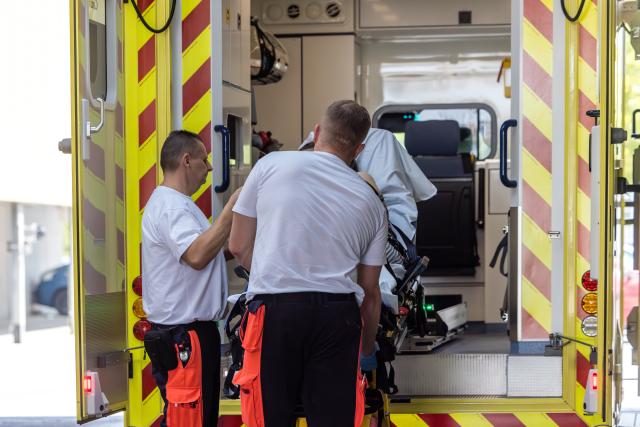 28 June 2026, Brandenburg, Cottbus: Paramedics at the emergency room of the Medical University of Lausitz - Carl Thiem are lifting a stretcher carrying a patient out of their ambulance. There has been an increase in emergency calls due to heat-related illnesses. Temperatures in the region are expected to reach around 40 degrees Celsius again today, Sunday. Photo: Frank Hammerschmidt/dpa