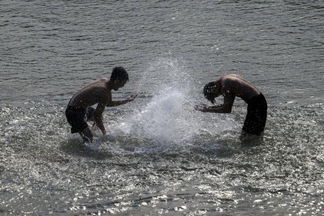 28 June 2026, Bavaria, Munich: Two men enjoy a refreshing dip in the waters of the Isar in the heart of the Bavarian capital. Photo: Peter Kneffel/dpa