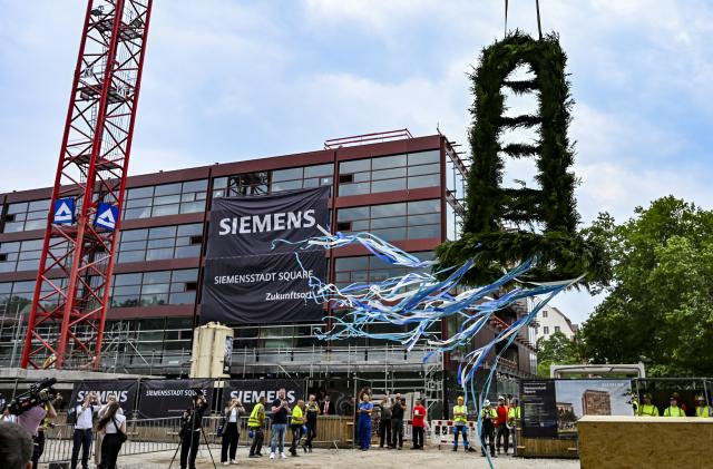 29 June 2026, Berlin: The Siemensstadt Square neighborhood is celebrating the topping-out ceremony for its first new buildings; the topping-out wreath is being put in place. Photo: Jens Kalaene/dpa