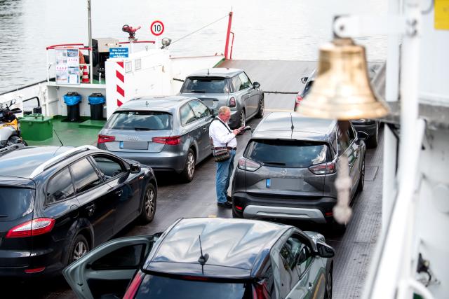 PRODUCTION - 18 June 2026, Hamburg: Ralph Rehlmeyer, the ticket collector on the "Hoopter Moewe 2" ferry, collects the fare from a driver for the trip between Zollenspieker and Hoopte. Photo: Daniel Bockwoldt/dpa