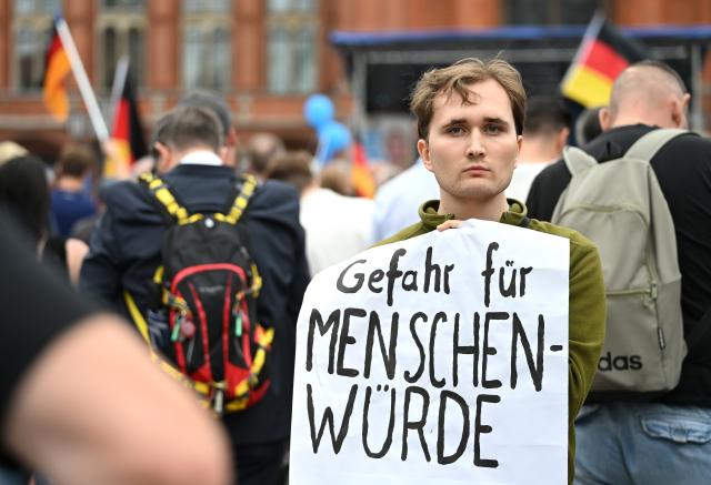 29 June 2026, Berlin: A protester stands in the crowd holding a sign that reads "Threat to Human Dignity" durin an Alternative for Germany (AfD) Berlin rally taking place in front of the Rotes Rathaus under the slogan "Berlin.Stark.Machen." (Make Berlin Strong) Photo: Elisa Schu/dpa