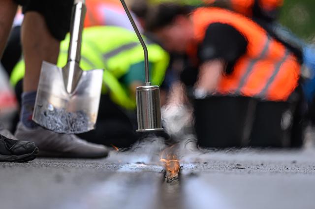 30 June 2026, Saxony, Leipzig: Volunteers scrape caked-on joint sealant from tram tracks in Leipzig city centre. Since 27 June 2026, virtually no trams have been running in the city due to heat damage to the tracks. The Leipzig Public Transportation Authority (LVB) has appealed to the public to help remove the oozed-out joint sealant. Photo: Hendrik Schmidt/dpa