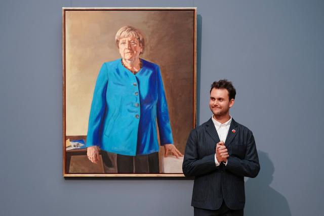 30 June 2026, Berlin: Artist Jeremie Queyras stands in front of the portrait of the former chancellor for the Hall of Fame at the German Chancellery. The portrait will be displayed at the Bode Museum until 4 October 2026 before being moved to the German Chancellery. Photo: Kay Nietfeld/dpa