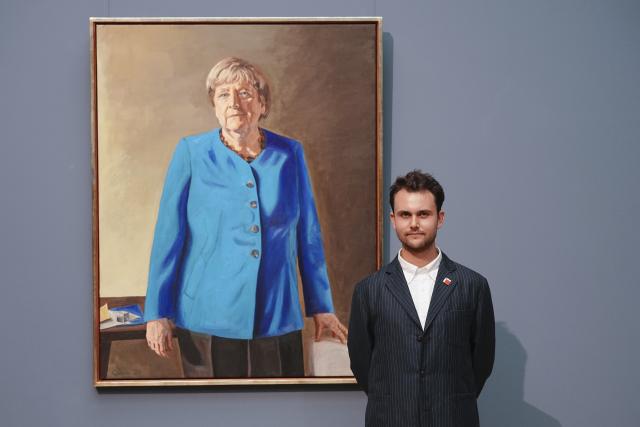 30 June 2026, Berlin: Artist Jeremie Queyras stands in front of the portrait of the former chancellor for the Hall of Fame at the German Chancellery. The portrait will be displayed at the Bode Museum until 4 October 2026 before being moved to the German Chancellery. Photo: Kay Nietfeld/dpa