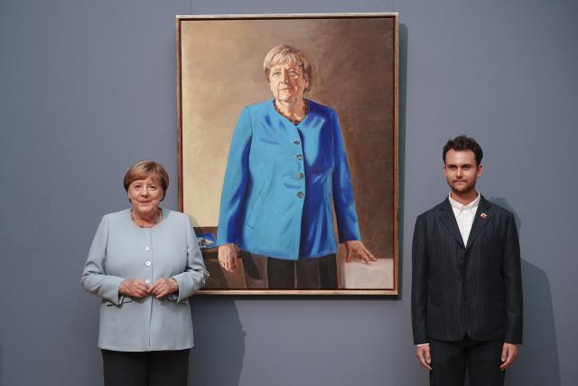 30 June 2026, Berlin: Angela Merkel (L), former Chancellor of Germany, and artist Jeremie Queyras stand in front of her portrait for the Hall of Ancestors at the German Chancellery. The painting will be displayed at the Bode Museum through 4 October 2026 before being moved to the Federal Chancellery. Photo: Kay Nietfeld/dpa