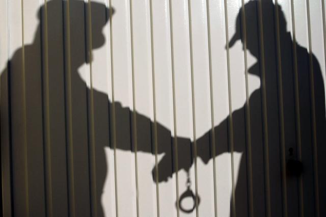 FILED - 20 February 2004, Bavaria, Lichtenfels: FILE PHOTO - A view of the shadow of a police officer handcuffing and detaining a person. Photo: Marcus Führer/dpa