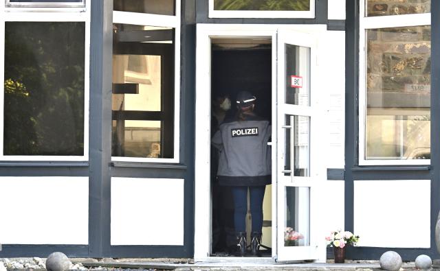 01 July 2026, North Rhine-Westphalia, Monschau: A police unit stands in the entrance to a building. Several people have died in a fire in this town in the Eifel region. Photo: Henning Kaiser/dpa