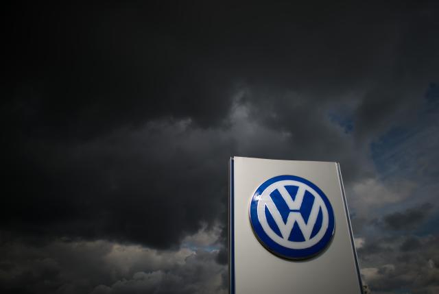 FILED - 22 September 2015, Lower Saxony, Wolfsburg: FILE PHOTO - Dark clouds pass over a Volkswagen logo at the Sandkamp gate of the VW plant in Wolfsburg. Photo: Julian Stratenschulte/dpa