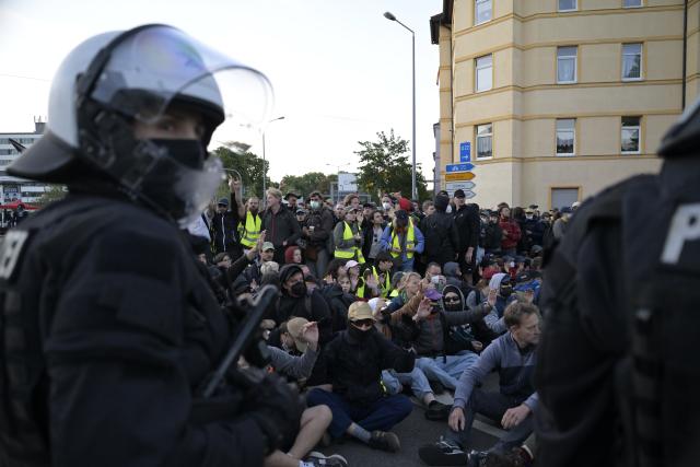 04 July 2026, Thuringia, Erfurt: Police officers in front of demonstrators blocking the access road to Erfurt's convention center, during a demonstration against the national party convention of the Alternative for Germany (AfD) pary. The AfD's national party convention is taking place on July 4 and 5 at the Erfurt Convention Center. Photo: Jacob Schröter/dpa