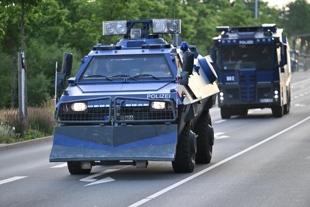 04 July 2026, Thuringia, Erfurt: An armored police vehicle and a water cannon on their way to the convention center, during a demonstration against the national party convention of the Alternative for Germany (AfD) party. The AfD's national party convention is taking place on July 4 and 5 at the Erfurt Convention Center. Photo: Martin Schutt/dpa
