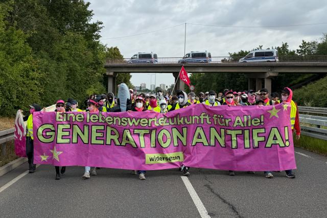 04 July 2026, Thuringia, Erfurt: Left-wing protestors hold a large banner during a demonstration against the national party convention of the Alternative for Germany (AfD) party. The AfD's national party convention is taking place on July 4 and 5 at the Erfurt Convention Center. Photo: Sven Kaeuler/dpa