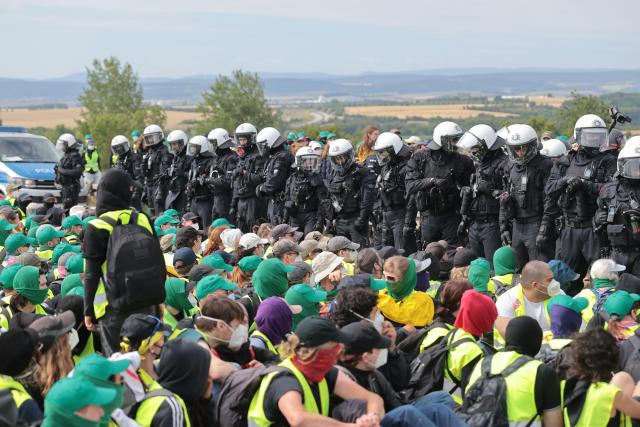 04 July 2026, Thuringia, Erfurt: Police officers surround protesters during a sit-in on the A71 highway north of the Erfurter Kreuz interchange near Molsdorf, during a demonstration against the national party convention of the Alternative for Germany (AfD) party. The AfD's national party convention is taking place on July 4 and 5 at the Erfurt Convention Center. Photo: Michael Reichel/dpa
