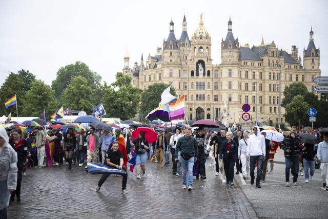 04 July 2026, Mecklenburg-Western Pomerania, Schwerin: Participants in a Christopher Street Day parade march past Schwerin Castle. Photo: Philip Dulian/dpa