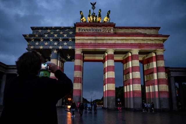 04 July 2026, Berlin: People look at the Brandenburg Gate, which is illuminated in the colors of the United States of America to mark the 250th anniversary of American independence. Photo: Fabian Sommer/dpa