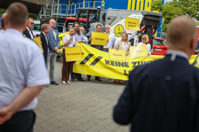06 July 2026, North Rhine-Westphalia, Duesseldorf: Representatives from several cities and municipalities in North Rhine-Westphalia hold signs and banners at a rally before leaving for Berlin. Photo: Christoph Reichwein/dpa