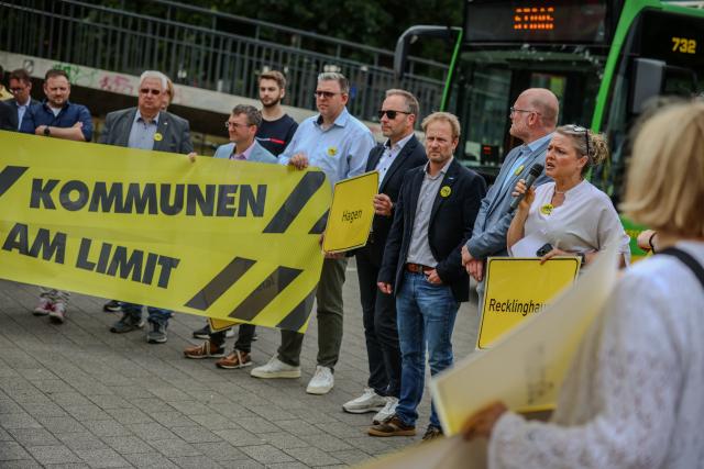 06 July 2026, North Rhine-Westphalia, Duesseldorf: Representatives from several cities and municipalities in North Rhine-Westphalia hold signs and banners at a rally before leaving for Berlin. Photo: Christoph Reichwein/dpa