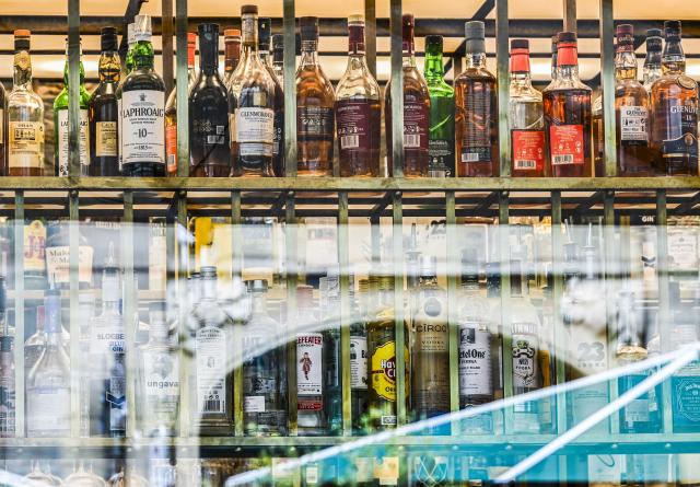 FILED - 06 July 2023, Berlin: FILE PHOTO - Bottles of various types of alcohol can be seen behind the windows of a bar. Photo: Jens Kalaene/dpa