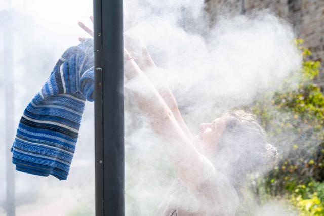 PRODUCTION - 07 July 2026, Lower Saxony, Hameln: Hamelin's climate adaptation manager Janine Moeller cools off at one of the city's misting stations during a hot weather. Photo: Swen Pförtner/dpa