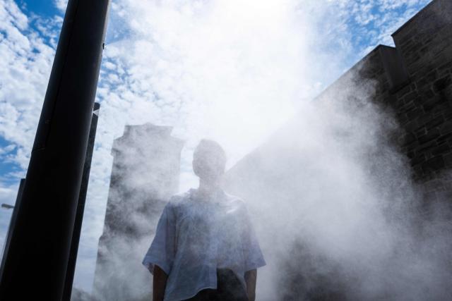 PRODUCTION - 07 July 2026, Lower Saxony, Hameln: A woman cools off at one of the city's misting stations during a hot weather. Photo: Swen Pförtner/dpa