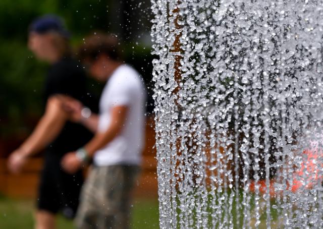 07 July 2026, Bavaria, Munich: Two men walk past a fountain in front of the Lenbachhaus. Photo: Sven Hoppe/dpa