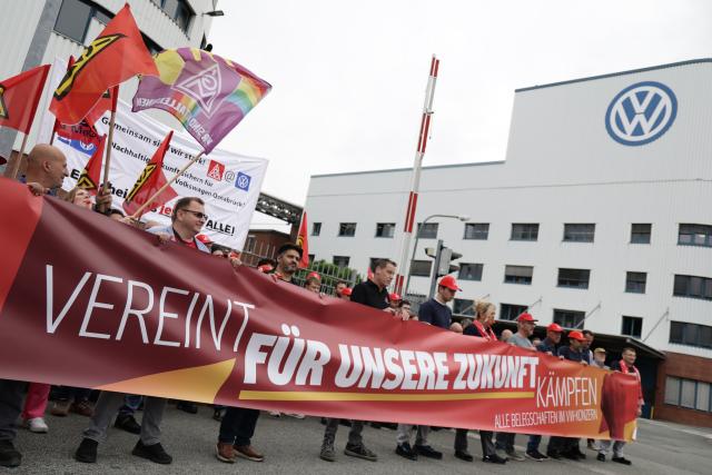 09 July 2026, Lower Saxony, Osnabrueck: People hold a large banner at a protest rally. Shop stewards, works council members, and youth and apprentice representatives from Volkswagen are taking part in an information and protest event organized by IG Metall in front of the VW plant in Osnabrueck, On the day of the Volkswagen AG supervisory board meeting in Wolfsburg. Photo: David-Wolfgang Ebener/dpa