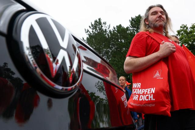 09 July 2026, Lower Saxony, Wolfsburg: A person stands next to a Volkswagen vehicle while employees of the automaker and members of the IG Metall union are demonstrating on the grounds of Volkswagen's headquarters in Wolfsburg on the day of a supervisory board meeting. Photo: Lisi Niesner/Reuters/Pool/dpa