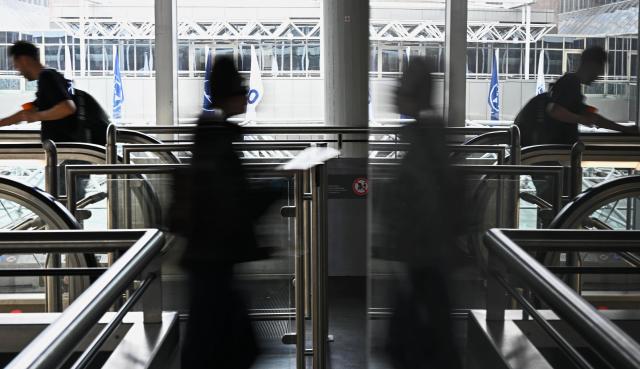09 July 2026, Hesse, Frankfurt am Main: Holidaymakers are reflected in a glass pane near an escalator in Terminal 1 at Frankfurt Airport. Around 63.2 million passengers passed through the airport in 2025. Photo: Jennifer Brückner/dpa