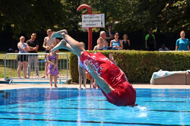 10 July 2026, Saxony-Anhalt, Wernigerode: A young man dives into the cool water at the Waldhofbad in Wernigerode as a participant in the cannonball championship. Photo: Matthias Bein/dpa