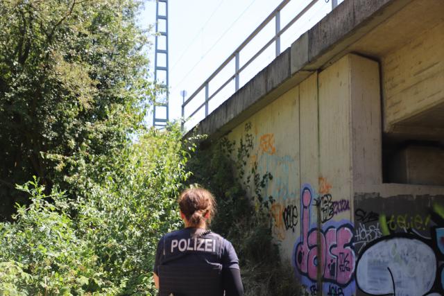 10 July 2026, North Rhine-Westphalia, Leverkusen: A police officer stands under a bridge along a railroad track. Following a fire on the embankment, the major railroad line between Duesseldorf and Cologne will remain closed until at least Saturday afternoon. Photo: Sascha Thelen/dpa