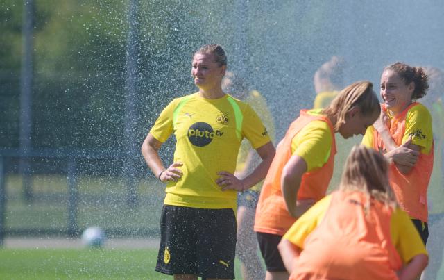 10 July 2026, North Rhine-Westphalia, Dortmund: New signing Alexandra Popp (L) stands in the mist from the sprinkler during Borussia Dortmund's First Training Session of the Season at DORTMUND-BRACKEL. Photo: Bernd Thissen/dpa