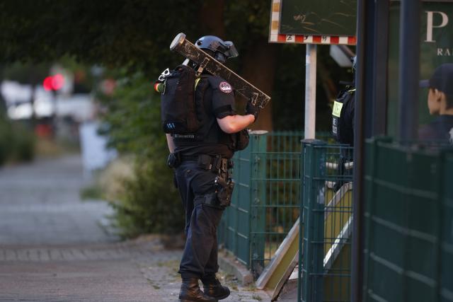 11 July 2026, Berlin: Police officers stand guard and secure a perimeter outside a supermarket, following reports of an active hostage situation inside the building. Special operations units have deployed to the scene, and local authorities have cordoned off the surrounding streets. Photo: Carsten Koall/dpa