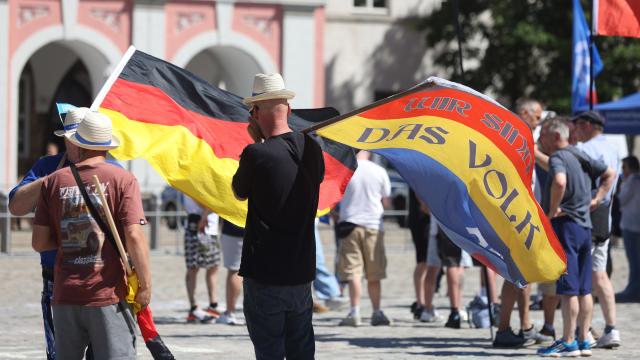 11 July 2026, Mecklenburg-Western Pomerania, Rostock: A participant in an Alternative for Germany (AfD) rally under the slogan "Stop Leftist Violence!" holds up a flag at Neuer Markt bearing the words "We Are the People". Photo: Danny Gohlke/dpa