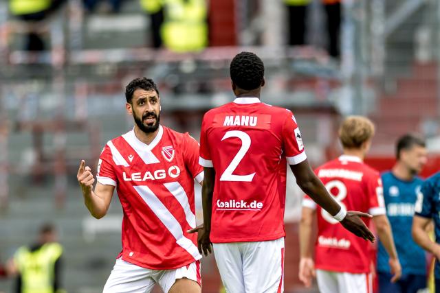 FILED - 09 May 2026, Cottbus: FILE PHOTO - Cottbus' Tolga Cigerci (L) gestures toward King Manu during the German 3rd Division (3. Liga) soccer match between Energie Cottbus and SV Wehen Wiesbaden at the LEAG Energie Stadium.  A pre-season friendly between German second-division newcomers Energie Cottbus and fourth-tier Halle was abandoned on Saturday due to racist remarks from the crowd, as Cottbus player Manu was the subject of monkey noises and was verbal abuse by fans. Photo: Frank Hammerschmidt/dpa