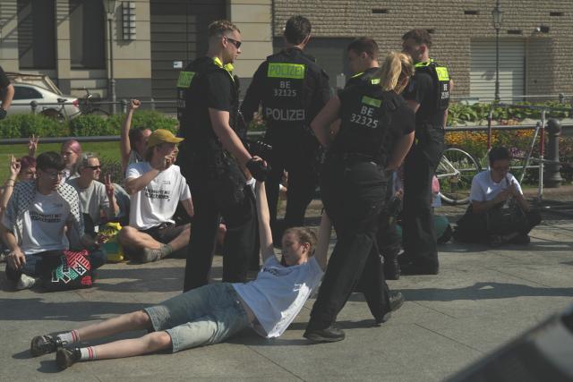 13 July 2026, Berlin: Police officers lead an activist away from the Brandenburg Gate during a protest against defence contractor Rheinmetall in Berlin. Photo: Sven Kaeuler/dpa