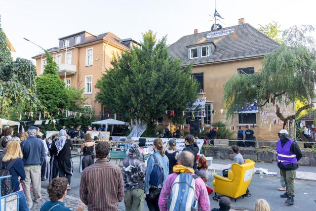 14 July 2026, Hesse, Giessen: A crowd gathers outside a building at Justus Liebig University Giessen on Hein-Heckroth-Strasse, as police prepare to clear the premises after activists occupied the building on Saturday. Photo: Christian Lademann/dpa