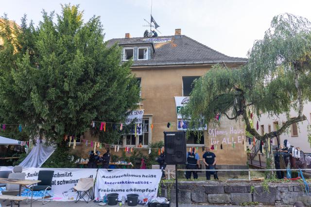 14 July 2026, Hesse, Giessen: Police officers stand in front of a building displaying banners with various messages during the clearance of a building at Justus Liebig University Giessen on Hein-Heckroth-Strasse. The building has been occupied by activists since Saturday. Photo: Christian Lademann/dpa