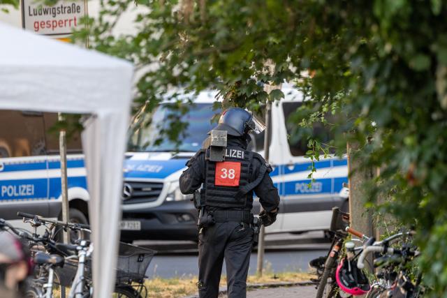14 July 2026, Hesse, Giessen: A police officer carries a battering ram during the clearance of an occupied building at Justus Liebig University Giessen on Hein-Heckroth-Strasse. The building has been occupied by activists since Saturday. Photo: Christian Lademann/dpa
