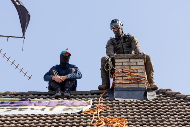 14 July 2026, Hesse, Gießen: A police officer from a special unit remains on the roof with an activist while another is being lowered down via a turntable ladder. Police are clearing the Justus Liebig University of Giessen building on Hein-Heckroth-Strasse, which has been occupied by activists since Saturday. Photo: Christian Lademann/dpa