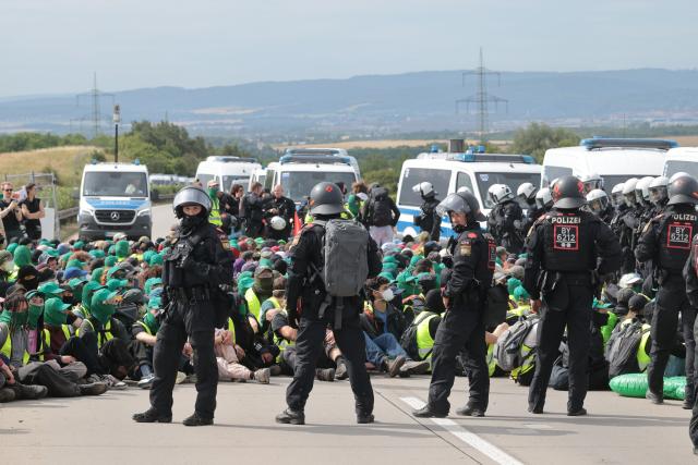 FILED - 04 July 2026, Thuringia, Erfurt: Police officers surround protesters during a sit-in on the A71 highway north of the Erfurter Kreuz interchange near Molsdorf. Photo: Michael Reichel/dpa
