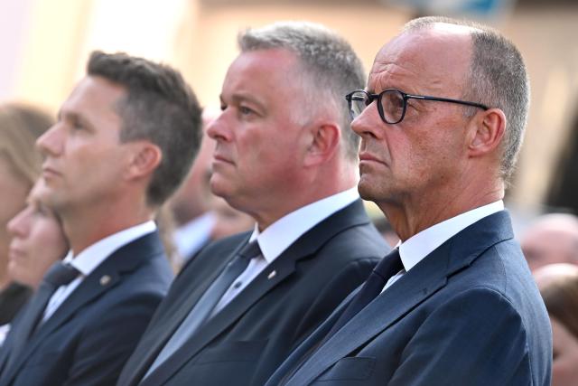 14 July 2026, Rhineland-Palatinate, Bad Neuenahr-Ahrweiler: (L-R) Pascal Rowald, mayor of Bad Neuenahr-Ahrweiler, Gordon Schnieder, Minister-President of Rhineland-Palatinate, and German Chancellor Friedrich Merz, attend the central memorial ceremony marking the fifth anniversary the 2021 European floods, in the Ahr Valley on the market square. During the flood disaster in the summer of 2021, 136 people died in Rhineland-Palatinate, 135 of them in the Ahr Valley. Photo: Jennifer Brückner/dpa