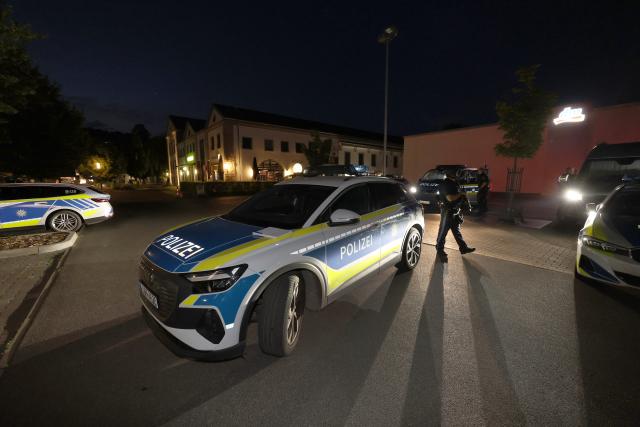 14 July 2026, Bavaria, Wuerzburg: Police officers gather at a staging area during a large-scale operation to search for a man with a gun in Wuerzburg. Police warned against picking up hitchhikers after receiving reports of several shots fired around 8:20 pm in the area of Unterduerrbacher street, according to a Lower Franconia Police spokesperson. Shots were fired into the air and at a building's facade. Photo: Karl-Josef Hildenbrand/dpa