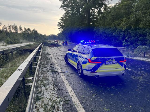 14 July 2026, Bavaria, Erlangen: Police secure a road blocked by fallen branches after a thunderstorm near Erlangen. Photo: News5 / Lars Haubner/NEWS5/dpa